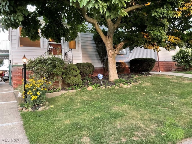 view of side of property with brick siding and a lawn