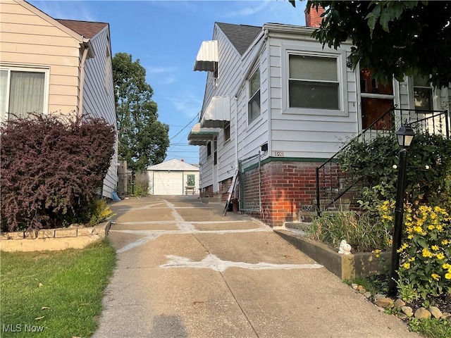 view of side of property featuring an outbuilding, concrete driveway, a detached garage, and a chimney