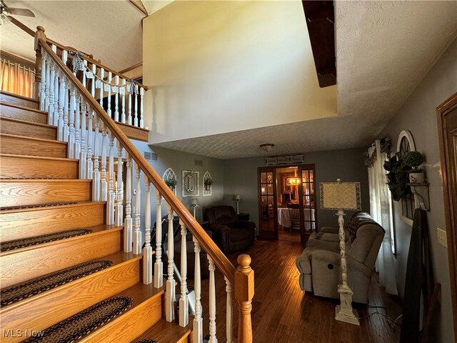 staircase with ceiling fan, hardwood / wood-style flooring, and a textured ceiling