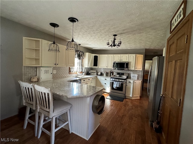 kitchen featuring pendant lighting, a textured ceiling, stainless steel appliances, dark hardwood / wood-style flooring, and kitchen peninsula