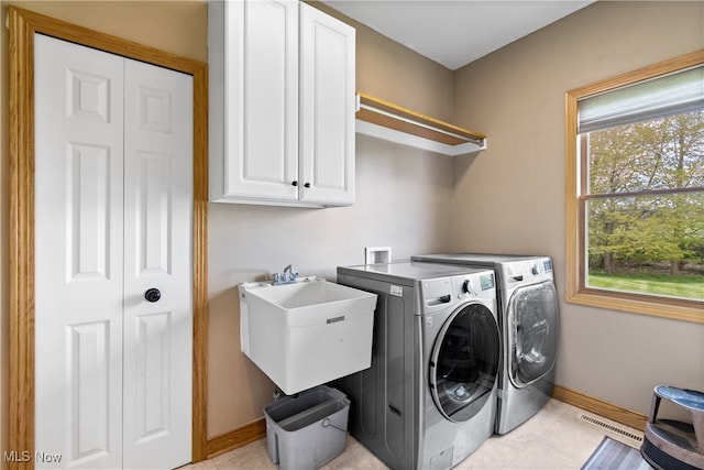 laundry area with sink, light tile patterned flooring, separate washer and dryer, and cabinets