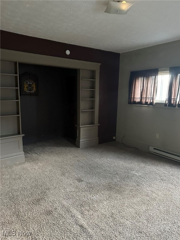 spare room featuring carpet, a textured ceiling, baseboard heating, and built in features