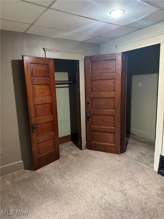 unfurnished bedroom featuring a drop ceiling, carpet floors, and a closet