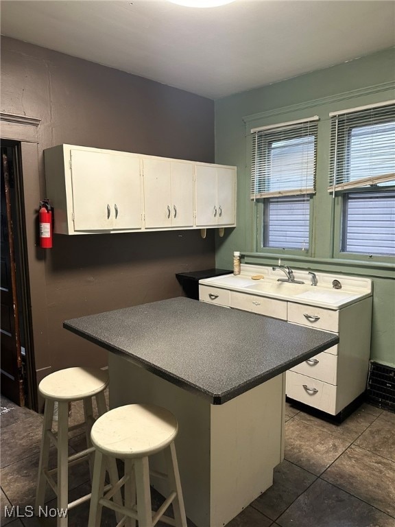 kitchen featuring sink, dark tile patterned floors, and white cabinets