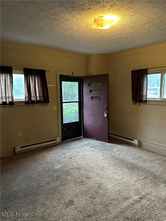 empty room with a wealth of natural light, a baseboard radiator, and carpet