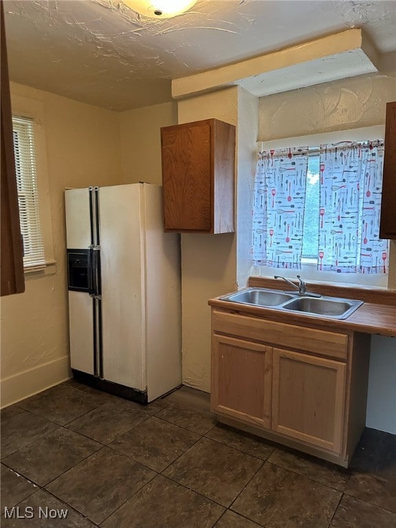 kitchen with white fridge with ice dispenser, sink, and dark tile patterned flooring