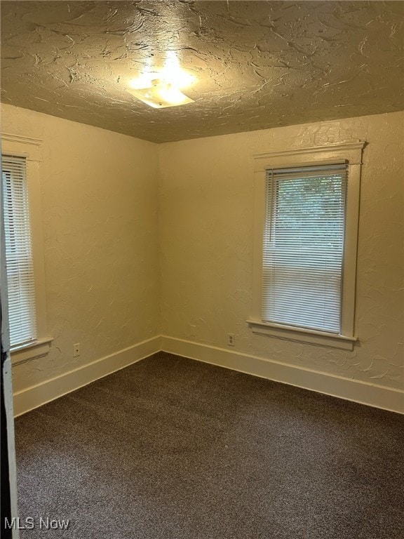 empty room with carpet and a textured ceiling