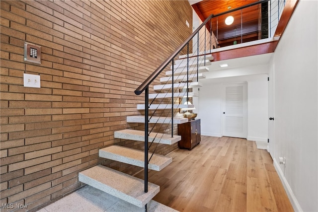 stairway featuring brick wall and a towering ceiling