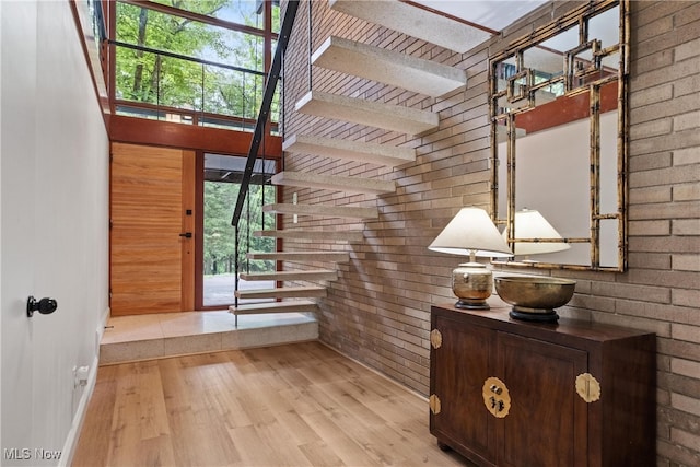 entryway featuring brick wall, a healthy amount of sunlight, and light wood-type flooring