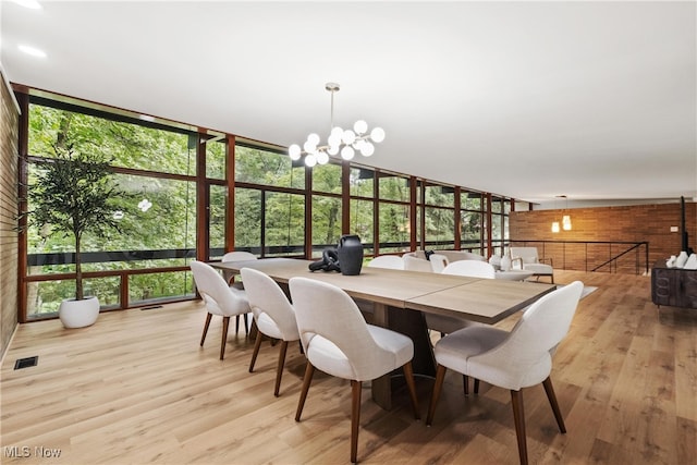 dining space with an inviting chandelier, light hardwood / wood-style flooring, and expansive windows