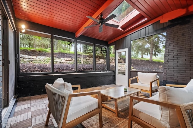 sunroom / solarium featuring wood ceiling, plenty of natural light, ceiling fan, and lofted ceiling with skylight