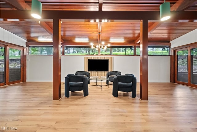 living area featuring a notable chandelier, light hardwood / wood-style flooring, and beamed ceiling