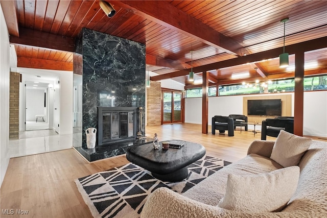 living room with beam ceiling, light hardwood / wood-style floors, a premium fireplace, and wood ceiling