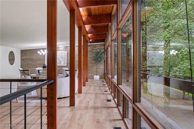 corridor featuring light wood-type flooring, a chandelier, wood ceiling, beam ceiling, and expansive windows