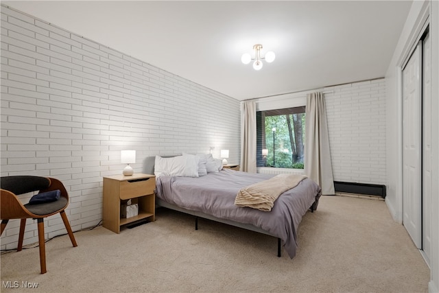 carpeted bedroom featuring a closet, brick wall, and a chandelier