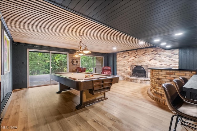 playroom featuring pool table, brick wall, a brick fireplace, light hardwood / wood-style floors, and wooden ceiling