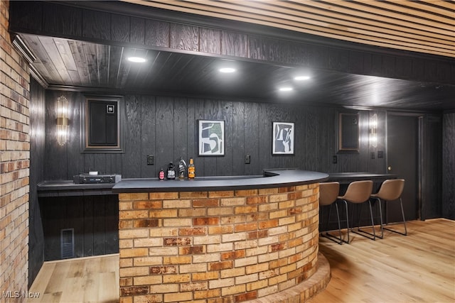 bar featuring wooden ceiling, light hardwood / wood-style flooring, and wooden walls