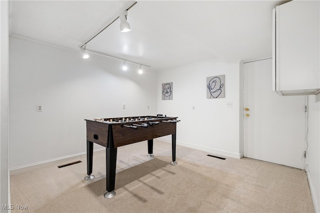 recreation room featuring crown molding, track lighting, and light carpet