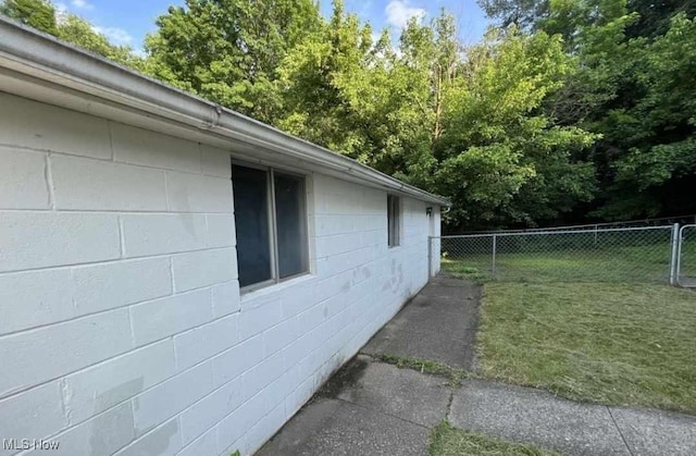 view of side of property featuring a yard, concrete block siding, and fence