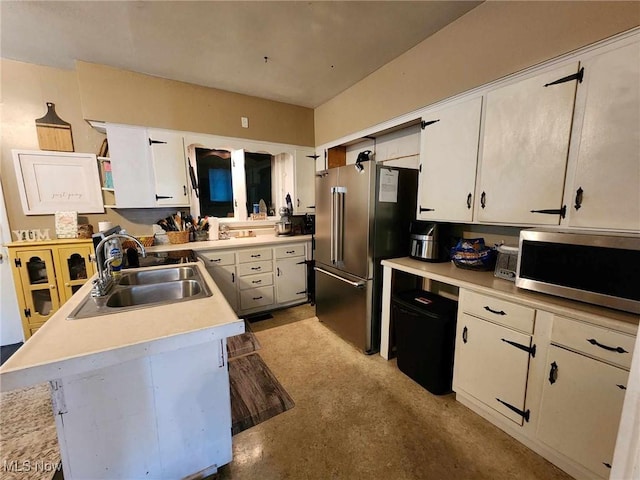 kitchen with light countertops, appliances with stainless steel finishes, a sink, and white cabinets