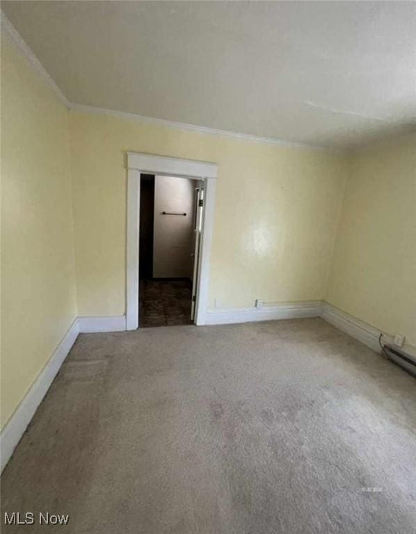 carpeted spare room featuring ornamental molding and baseboards