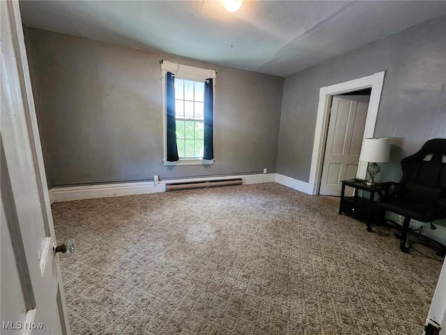 interior space featuring a baseboard heating unit, carpet floors, and baseboards