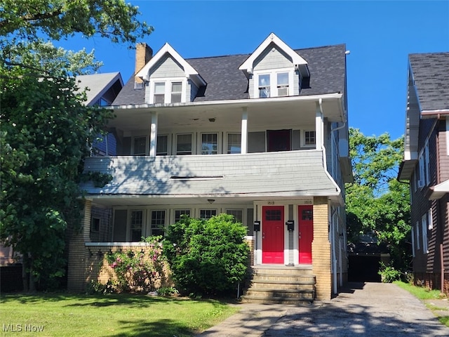 new england style home with a balcony and a front yard