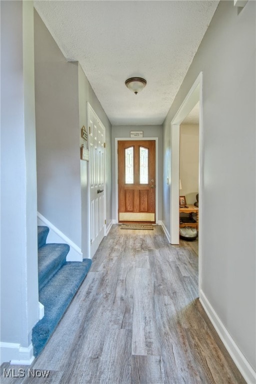 foyer entrance featuring a textured ceiling and light hardwood / wood-style flooring