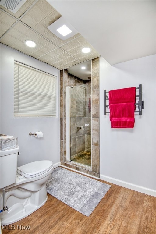 bathroom with an enclosed shower, toilet, and wood-type flooring