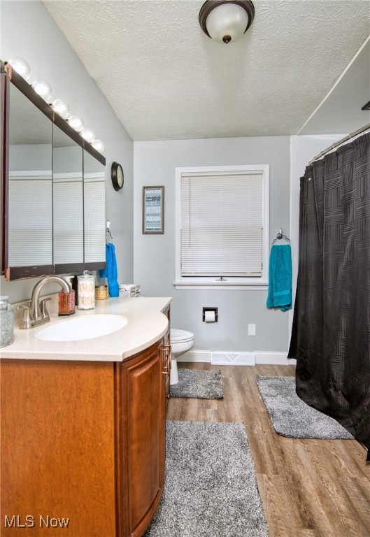 bathroom with a textured ceiling, toilet, vanity, and hardwood / wood-style flooring