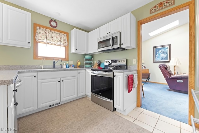 kitchen with light carpet, white cabinets, stainless steel appliances, and sink