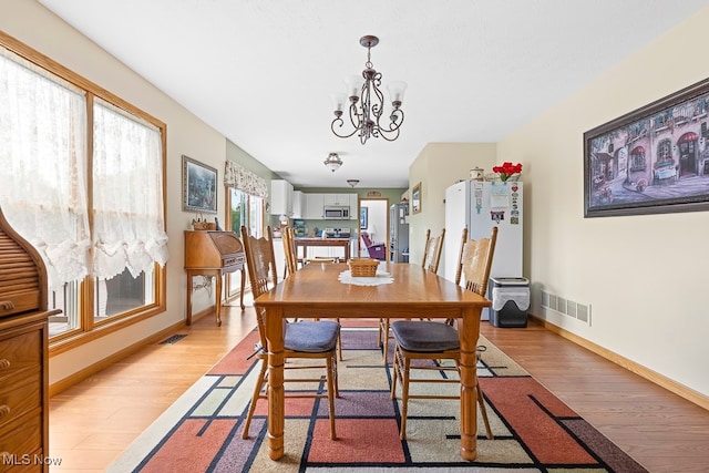 dining room with a chandelier, light hardwood / wood-style floors, and plenty of natural light