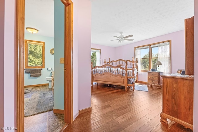 bedroom with connected bathroom, a textured ceiling, and wood-type flooring