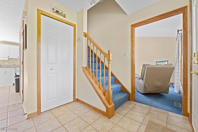 stairs with tile patterned floors and vaulted ceiling