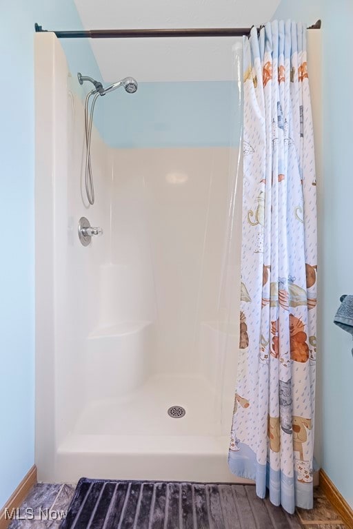 bathroom with a shower with shower curtain and hardwood / wood-style flooring