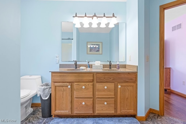 bathroom featuring toilet, vanity, and wood-type flooring