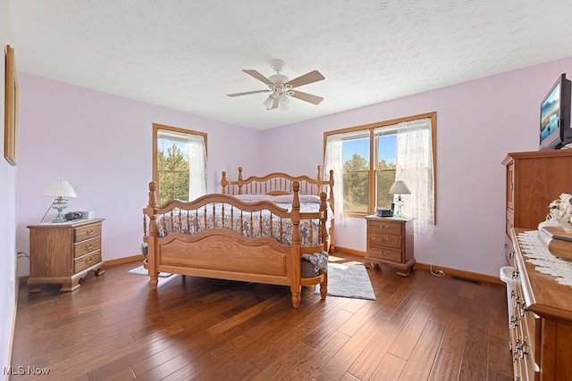 bedroom with dark wood-type flooring, multiple windows, a textured ceiling, and ceiling fan