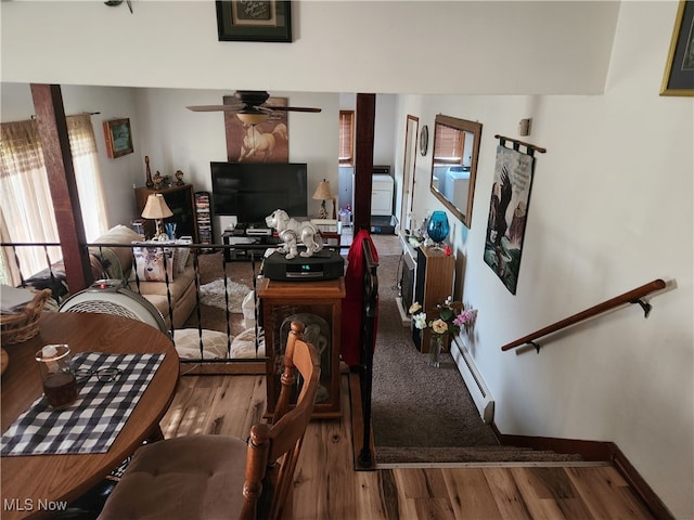 dining area with a baseboard heating unit, wood-type flooring, and ceiling fan