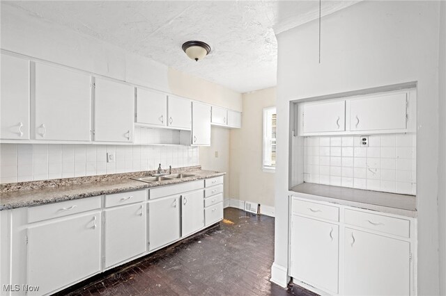 kitchen with backsplash, sink, dark hardwood / wood-style floors, and white cabinets