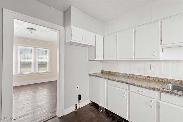 kitchen featuring dark wood-style floors, baseboards, white cabinetry, and decorative backsplash