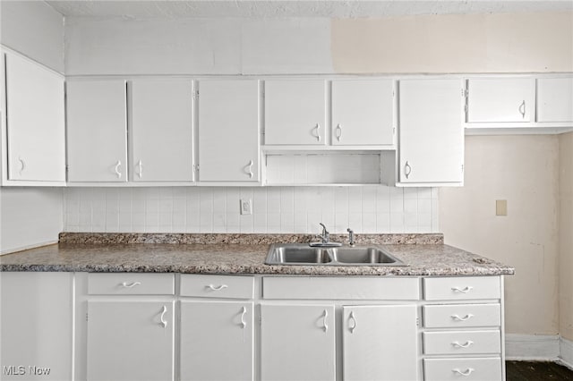 kitchen featuring white cabinetry, sink, and tasteful backsplash