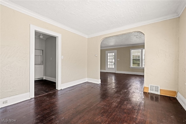 empty room with arched walkways, visible vents, a textured wall, dark wood-type flooring, and a textured ceiling