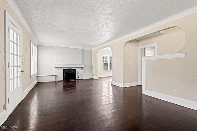 unfurnished living room with arched walkways, dark wood-style flooring, crown molding, a fireplace, and a textured ceiling