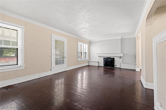 unfurnished living room featuring crown molding, dark wood finished floors, a fireplace, a textured wall, and a textured ceiling