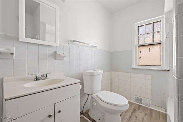 bathroom with tile walls, wood-type flooring, vanity, and toilet