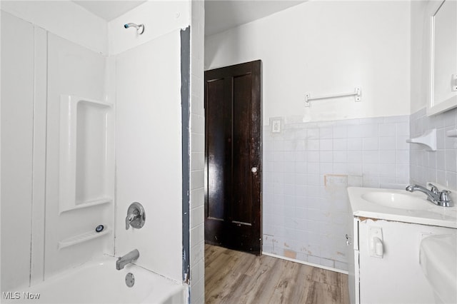 full bathroom featuring shower / bath combination, a wainscoted wall, wood finished floors, vanity, and tile walls