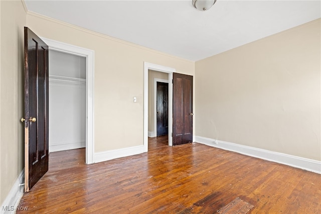 unfurnished bedroom featuring a closet, baseboards, and dark wood-type flooring