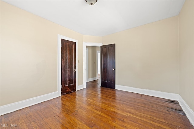 unfurnished room with wood-type flooring and baseboards