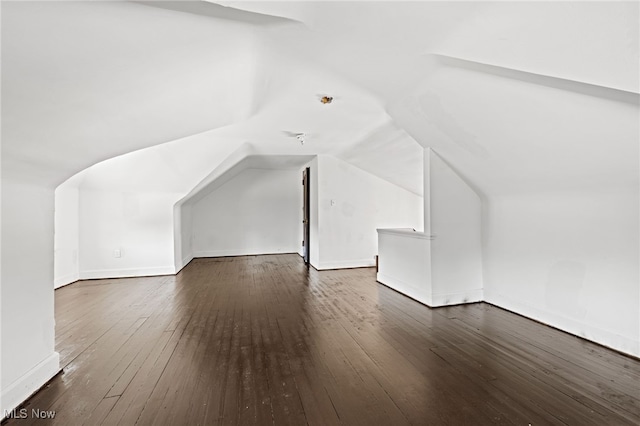 bonus room with vaulted ceiling, dark wood-style flooring, and baseboards