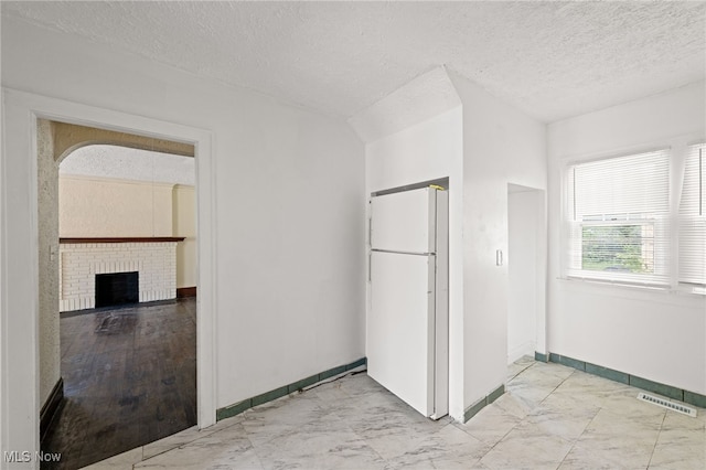 interior space with baseboards, visible vents, marble finish floor, a textured ceiling, and a fireplace